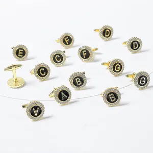 Detailed view of round gold cufflinks with crystal halo and black letter engraving