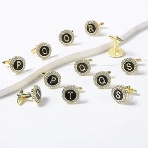 Detailed macro view of gold-plated alphabet cufflinks with black enamel and crystals