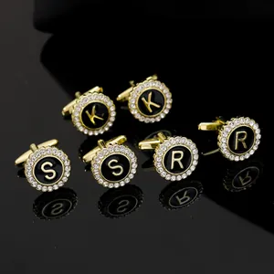 Macro shot of gold-plated round cufflinks with halo crystals and letter engraving