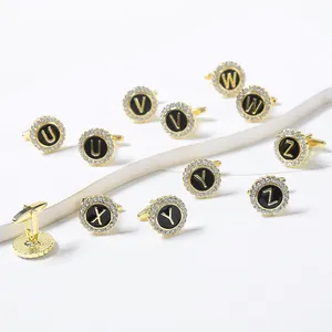 Detailed view of round gold-plated cufflinks with black enamel and alphabet crystal inlay