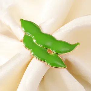 Dettaglio macro di un portatovagliolo a baccello in smalto verde con bordi dorati