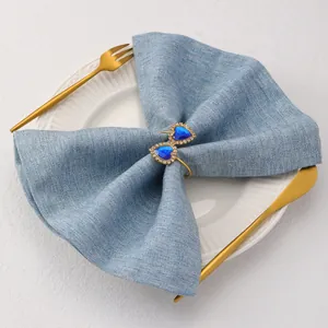Close-up of heart-shaped blue gemstone napkin ring on a blue cloth with golden tableware