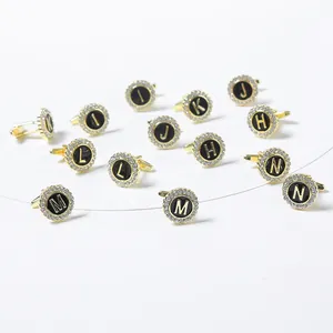 Macro view of gold cufflinks with black enamel letters and white rhinestone inlay