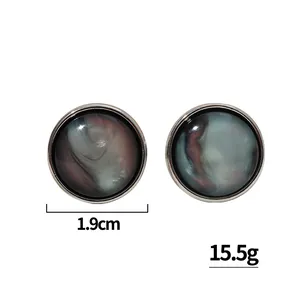 Detalle de gemelos redondos de 1,9cm con textura de mármol y marco de plata elegante