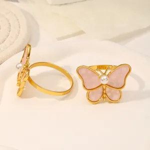 Detalle de servilleteros de mariposa dorados con perla y alas con textura mármol