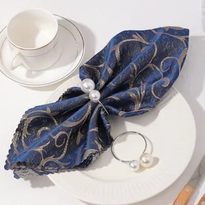 Servilleteros de plata con perlas dobles sobre elegantes servilletas de tela azul