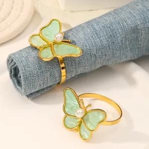 Detalle de servilletero mariposa con esmalte verde pálido y perla sobre marco dorado