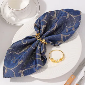 Vue détaillée d'un rond de serviette doré 'Love' sur un tissu bleu marine élégant