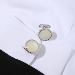 Detalle de gemelos redondos plateados con cristal en el puño de camisa blanca