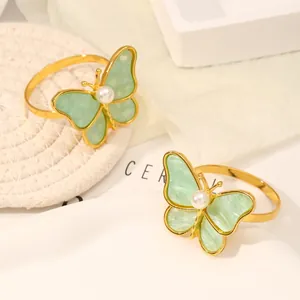Detalle del servilletero de mariposa dorada con alas de mármol verde y detalle de perla blanca