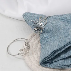 Dettaglio di portatovaglioli a loto in argento su denim blu per decorazione tavola