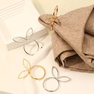 Detail van gouden en zilveren servetringen in de vorm van konijnenoren op linnen doek