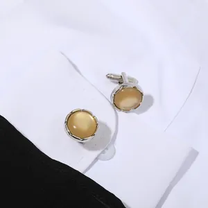 Detalle de gemelos redondos de plata con cristal ámbar en camisa blanca y traje