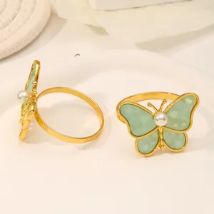 Detalle de los servilleteros de mariposa dorados con alas verdes y perla central
