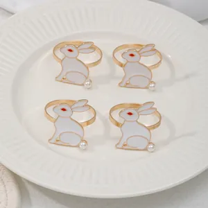 Detalle de cuatro servilleteros de conejo dorados con esmalte y perlas en un plato