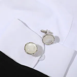 Detalle de gemelos de plata con nácar redondo en el puño de una camisa blanca