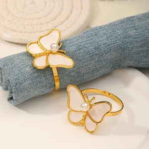 Elegantes servilleteros de mariposa dorados con nácar y servilletas de lino azul