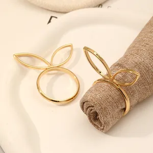 Detailopname van gouden servetringen met konijnenoren op een beige linnen servet