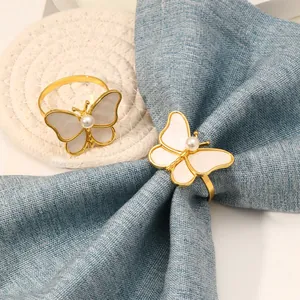 Detalle de servilletero mariposa dorada con perla y nácar sobre servilleta azul