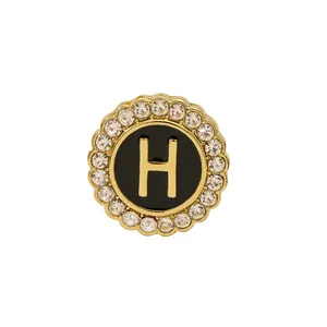Elegant gold round brooch with black enamel, crystal rhinestones and capital letter H