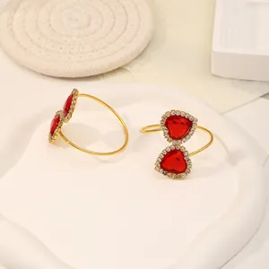 Detail of gold heart napkin rings with red crystals and diamond accents for wedding decor