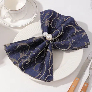Detalle de servilletero con doble perla sobre servilleta floral azul marino