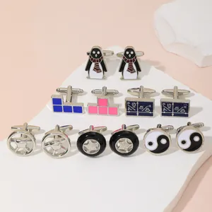 Dettaglio di gemelli creativi in metallo con motivi a pinguino, scala e yin-yang