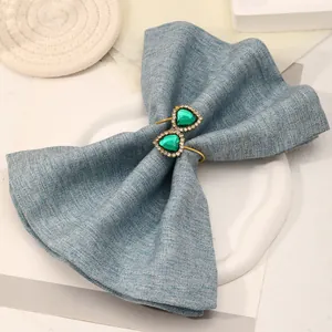 Detail shot of golden double heart napkin rings with green gemstones and rhinestones