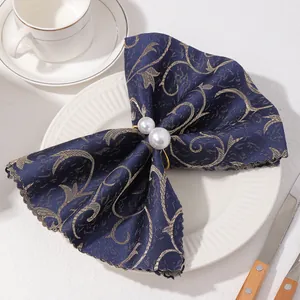 Detalle de servilleta floral azul y oro con servilletero de doble perla en plato blanco