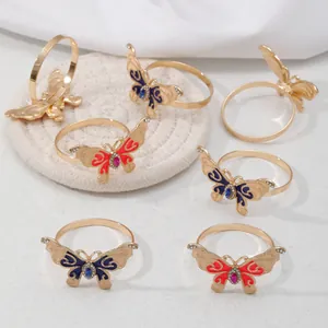 Elegantes servilleteros de mariposa dorada con esmalte rojo y azul y cristales brillantes