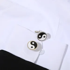 Dettaglio dei classici gemelli Tai Chi bianchi e neri su un polsino di camicia bianca