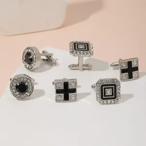 Macro view of men's silver cufflinks set with rhinestones on a white marble display base