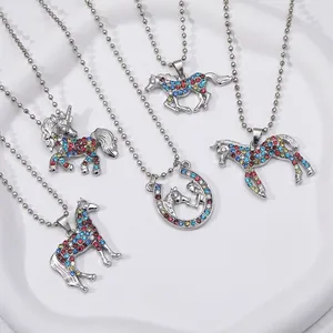 Macro view of five unicorn and horse necklaces with colorful rhinestones on a white plate