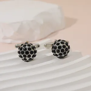 Macro shot of silver cufflinks with black pavé crystals on white geometric stand