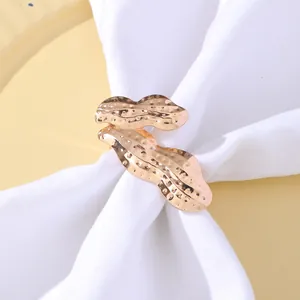 Dettaglio portatovagliolo a forma di arachide in oro rosa con trama martellata