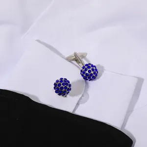 Classic silver-tone cufflinks with round blue crystals on a white dress shirt cuff