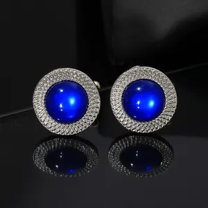 Silver-tone round cufflinks with blue cat-eye stone and geometric textured edge