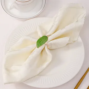 Dettaglio di un portatovagliolo a foglia verde con venature oro su piatto bianco