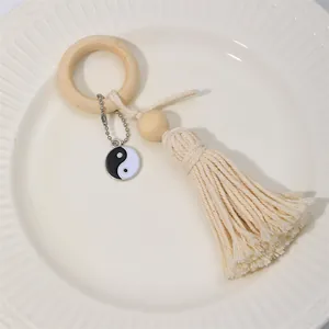 Wooden bead napkin ring with cotton tassel and Yin Yang charm in a white ceramic dish