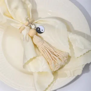 Close-up of wood bead napkin ring with cotton tassel and Tai Chi Yin Yang charm detail