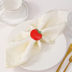 Dettaglio portatovagliolo a forma di pomodoro smaltato rosso su elegante piatto piano
