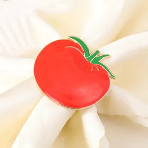 Dettaglio di un portatovagliolo a forma di pomodoro rosso lucido su tessuto bianco
