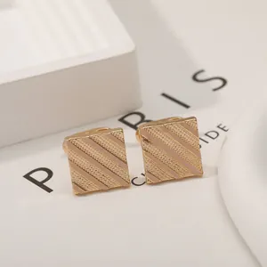 Detailed macro view of gold square cufflinks with elegant diagonal striped texture