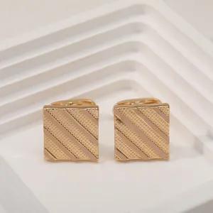 Close-up of square gold cufflinks featuring elegant pink enamel diagonal stripes