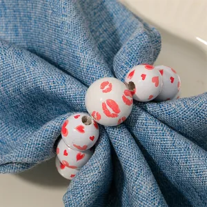 Close-up of wooden bead napkin ring with red heart and lip prints on blue fabric