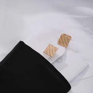 Close-up of rose gold square cufflinks with stripes on a white French shirt cuff