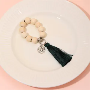 Detail of wooden bead napkin ring with owl charm, star pendant and green tassel on white plate