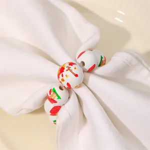 Detail of wooden bead napkin ring with Autumn leaf pattern on a white cloth napkin