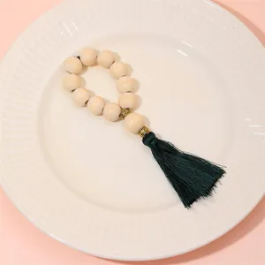 Detail of wooden bead napkin ring featuring dark green tassel on ceramic plate