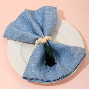 Detail of wooden bead napkin ring with green tassel and gold clasp on a white plate